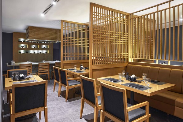 A restaurant with wooden furniture, a seating area, and a kitchen in the background.
