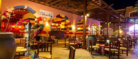 An outdoor restaurant with wooden tables and chairs, a large decorative vase, and a sign reading "nagaraja".