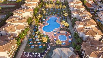 Una piscina al aire libre, sombrillas, tumbonas