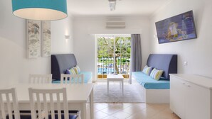 Un salon moderne comprenant une table à manger, deux canapés, un ventilateur de plafond et un téléviseur fixé au mur.