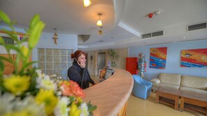 Un espace d’accueil avec un comptoir en bois, un canapé bleu et un divan beige.