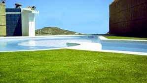 Un bâtiment moderne doté d’une piscine, d’une pelouse verdoyante et offrant une vue sur une montagne.