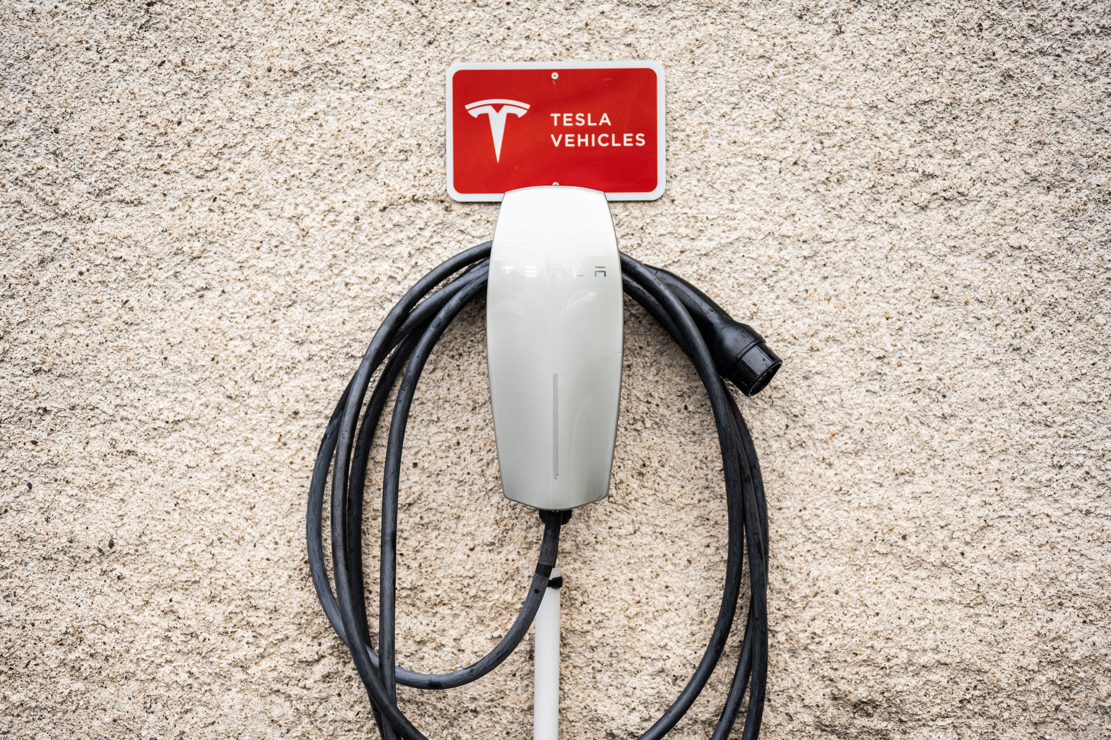 A Tesla charging station with a sign indicating it is for Tesla vehicles.