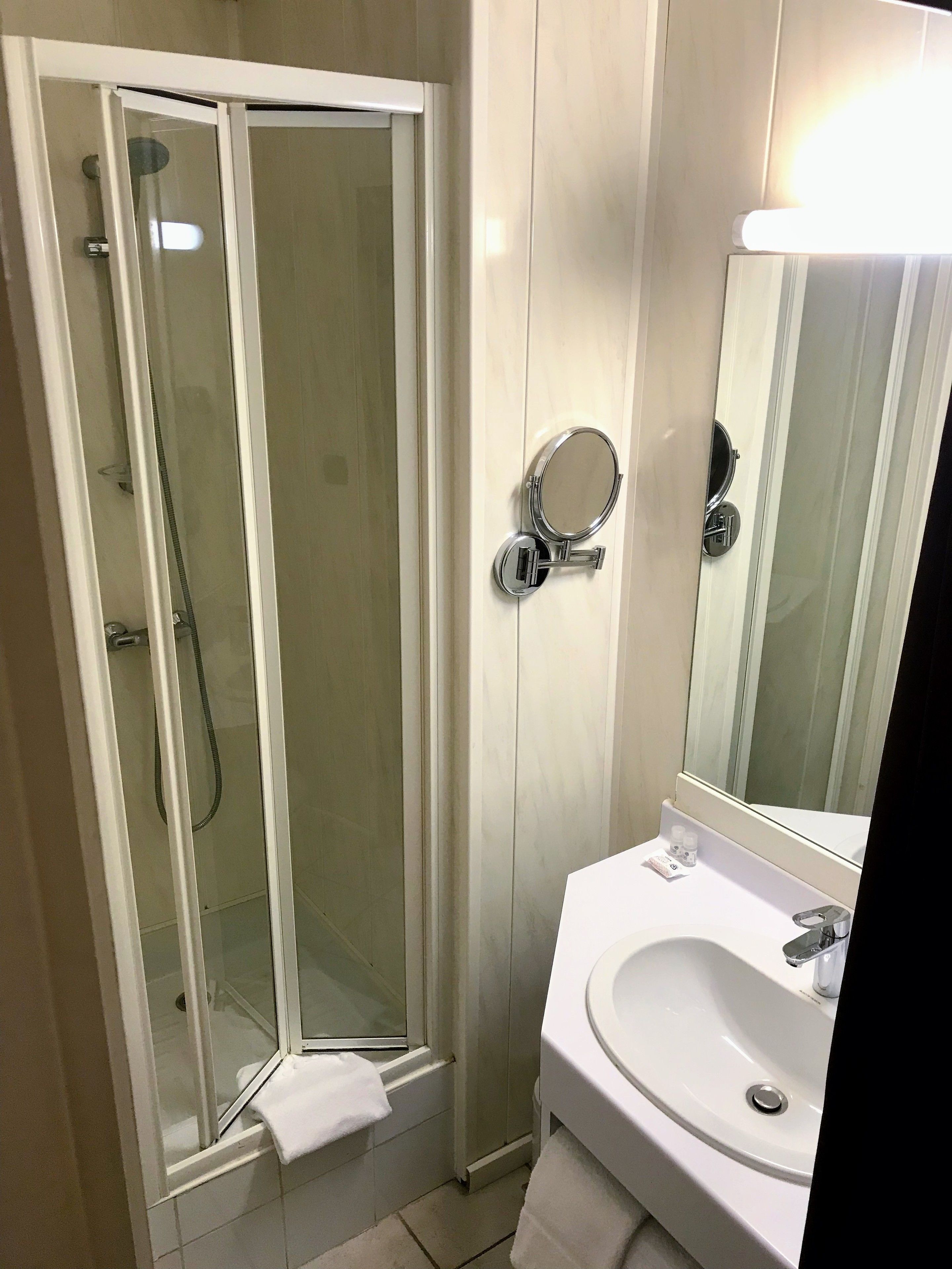 Baño con ducha de vidrio, lavamanos y espejo.