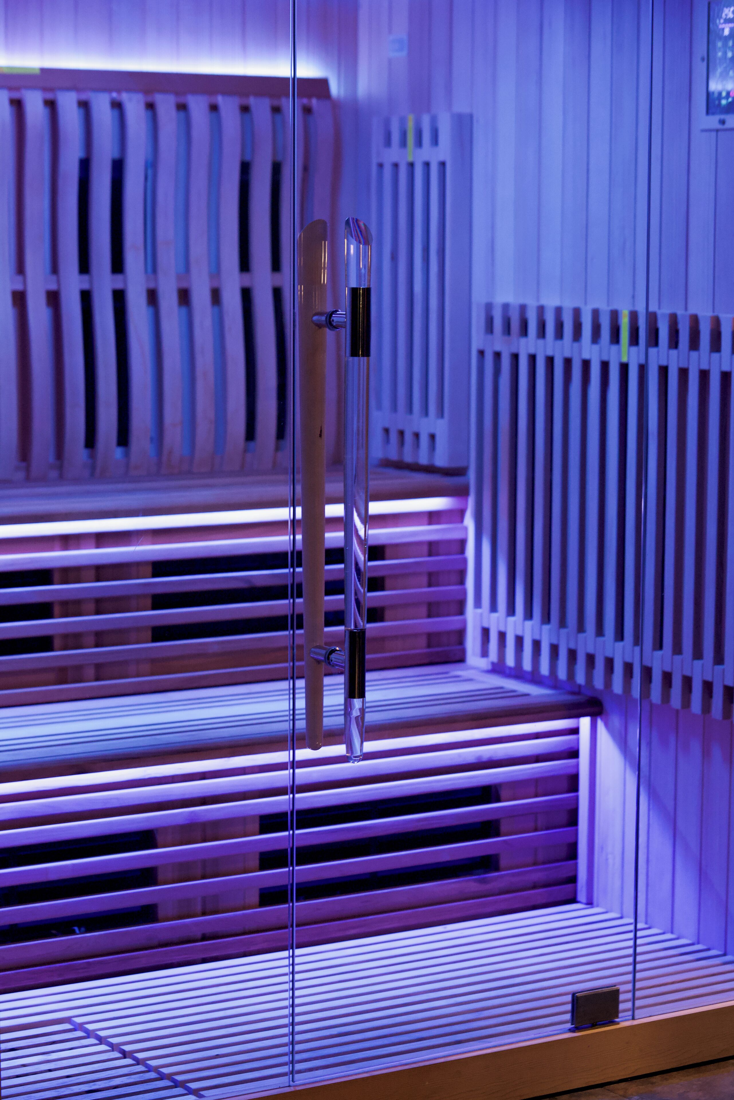 A sauna with wooden benches and a glass partition.