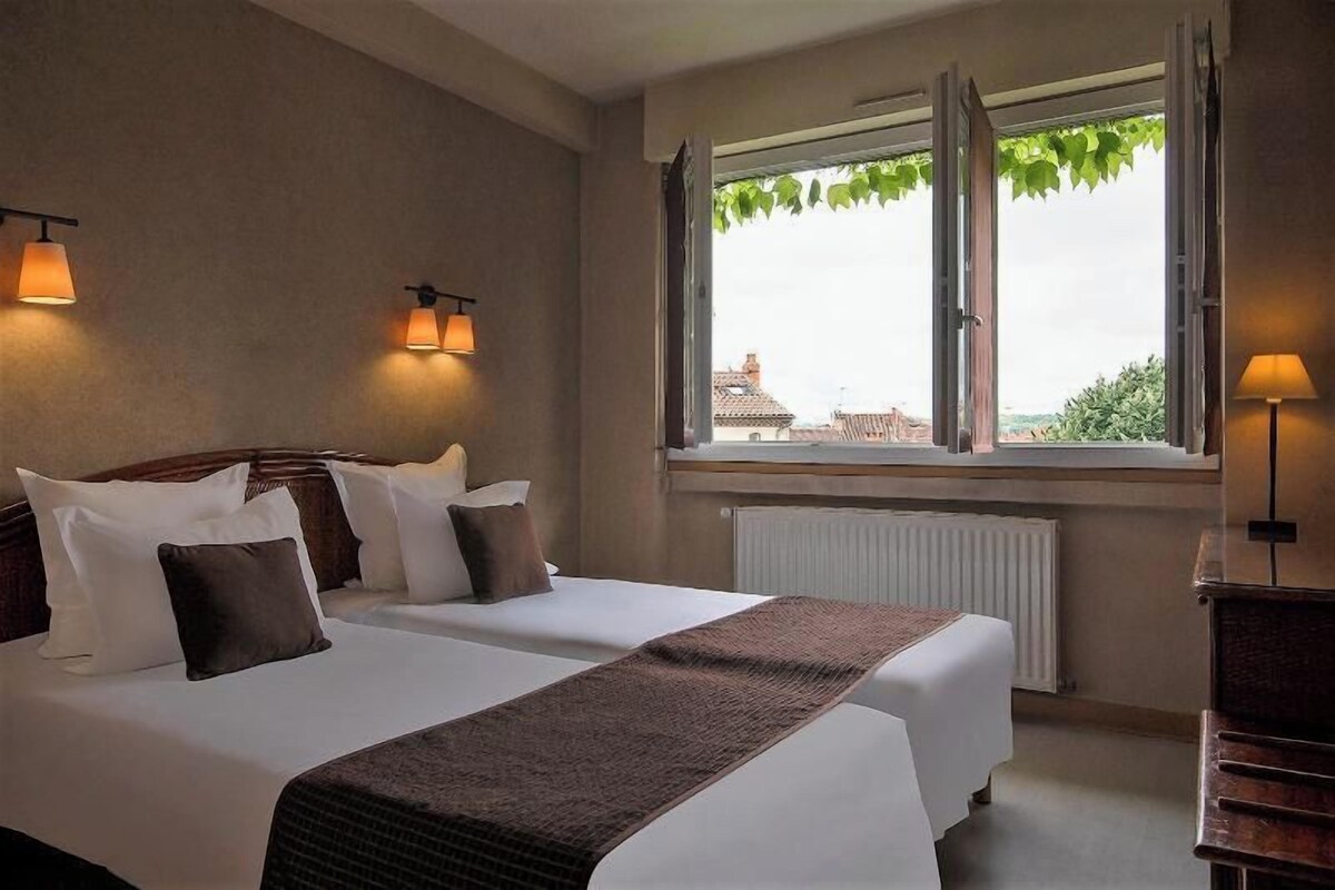Habitación de hotel con dos camas, una ventana con vistas y lámparas fijadas a la pared.