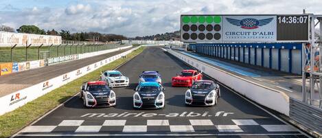 Una pista de carreras con cinco autos en la línea de salida, un temporizador digital mostrando 14:36:07 y el logotipo del Circuit d'Albi.