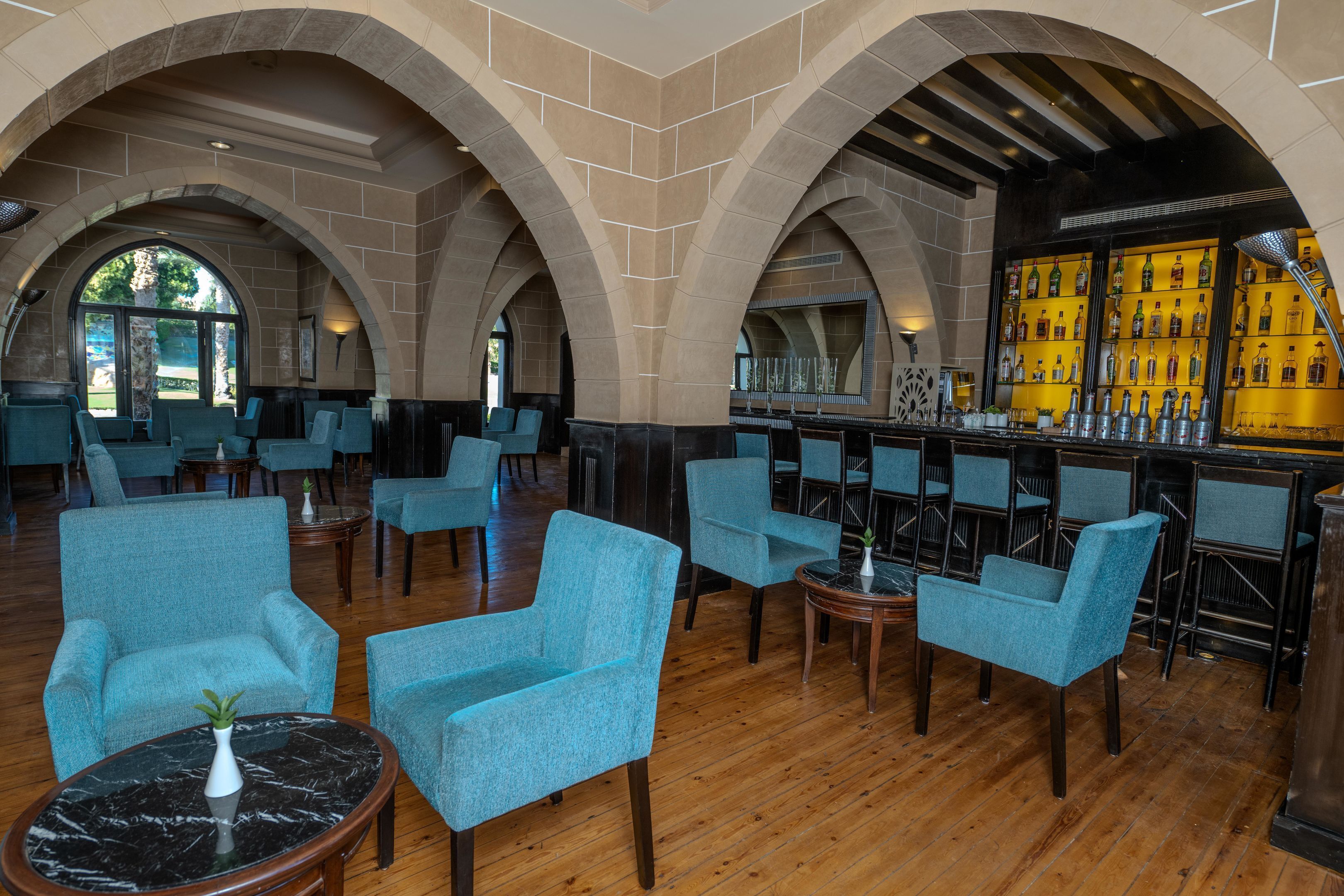 A lobby with arched ceilings, a bar area with bottles, and seating with a marble table.