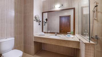 Une salle de bain équipée de toilettes, d’un lavabo, d’un miroir et d’une douche.