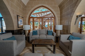 A lobby with a sofa, armchairs, a coffee table, and a ceiling with a wooden archway.