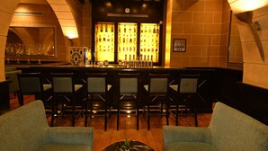 Eine Bar mit einer Theke, mehreren Barhocker und einer Spiegelwand.