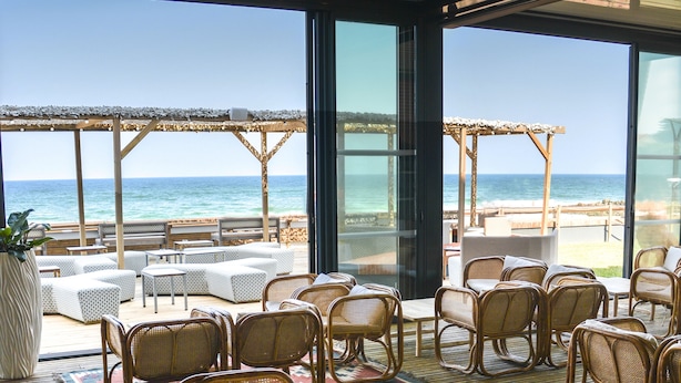 A beachside restaurant with wicker furniture and a view of the ocean.