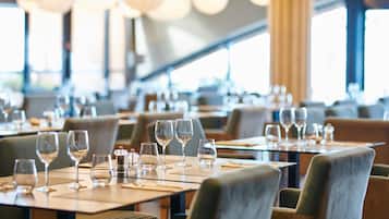 Een restaurantinterieur met gedekte tafels, helder glaswerk en een moderne kroonluchter.