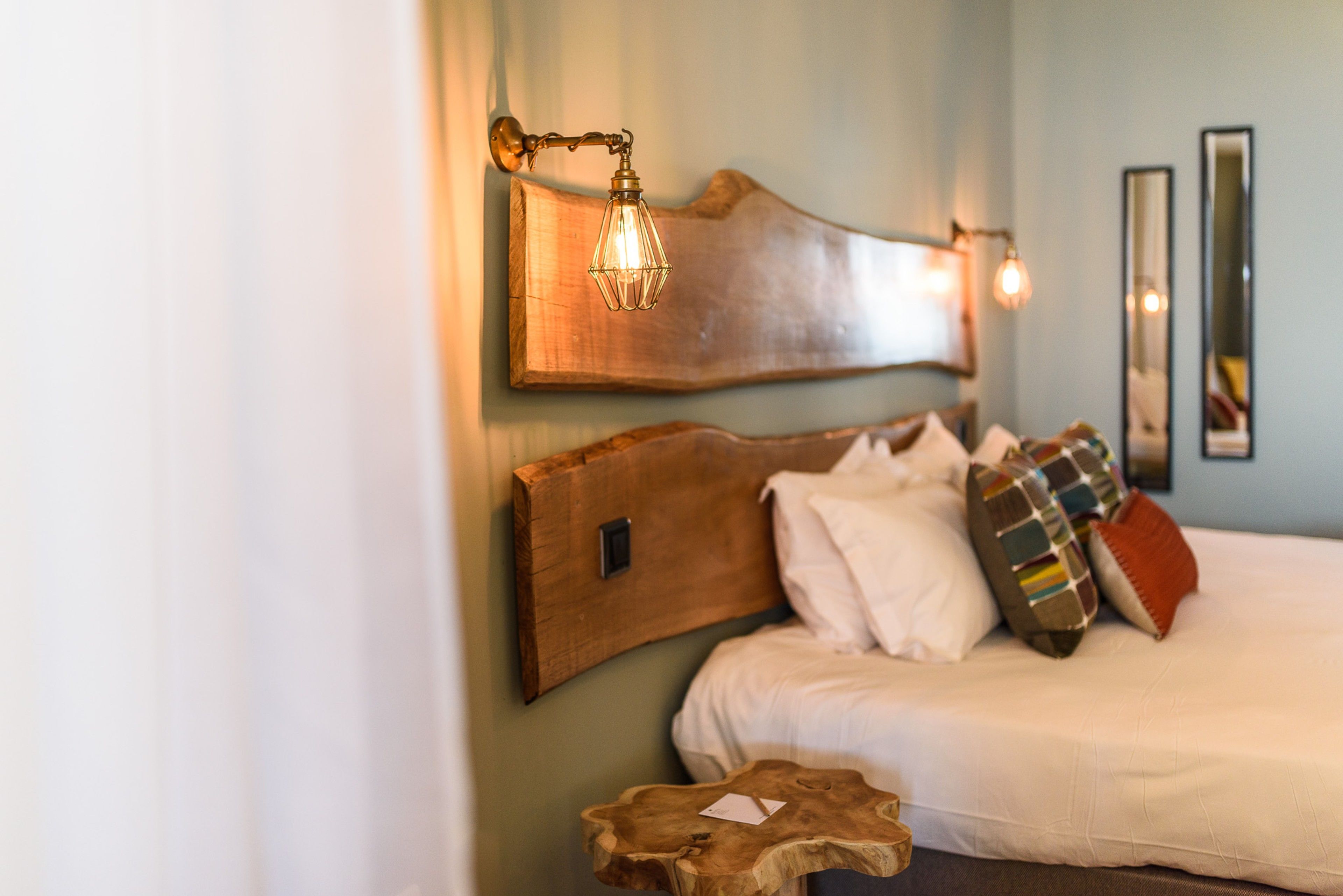 Un dormitorio con cabecera de madera, una mesita de noche y un espejo en la pared.