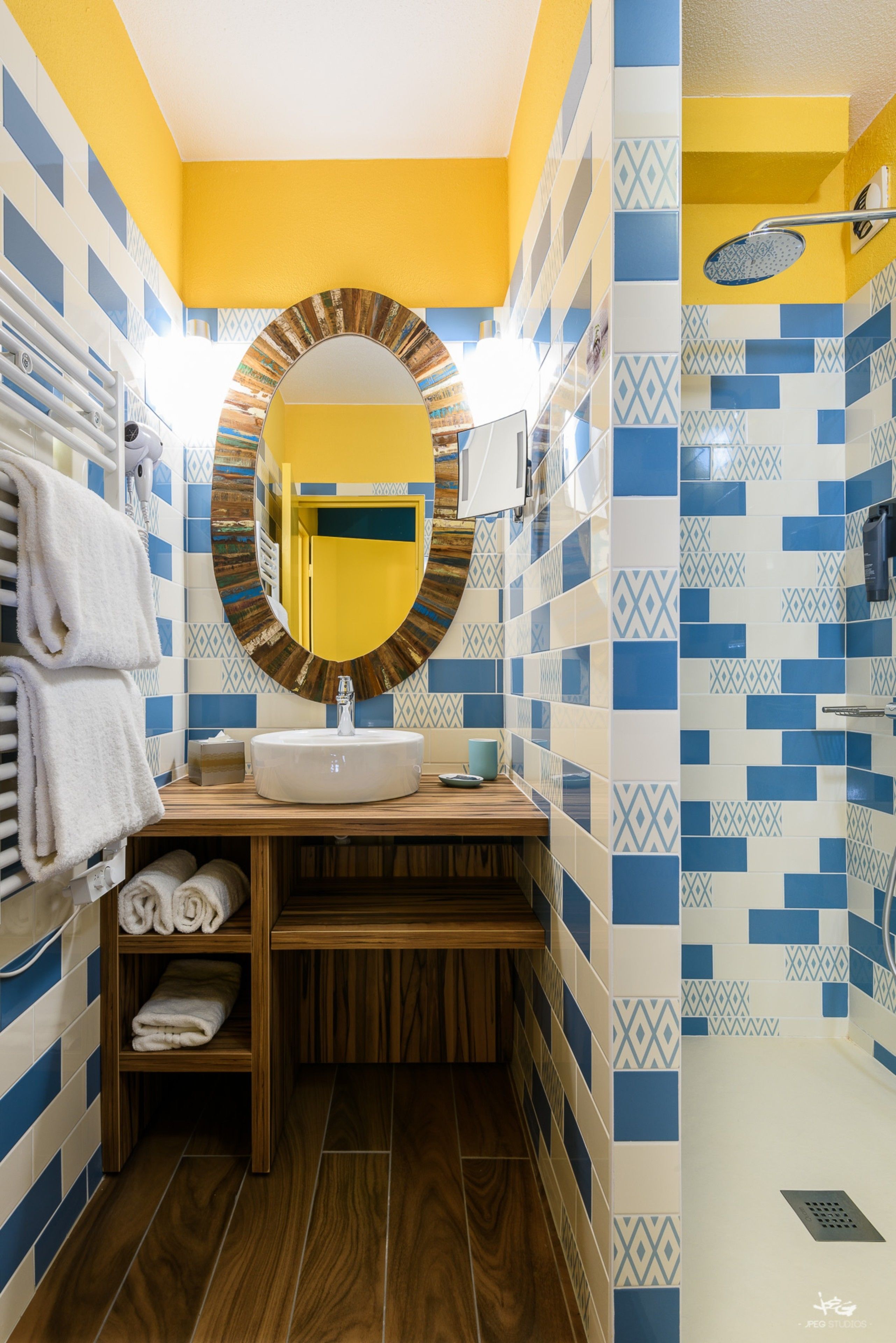 Un baño con tocador de madera, espejo redondo y lavamanos.