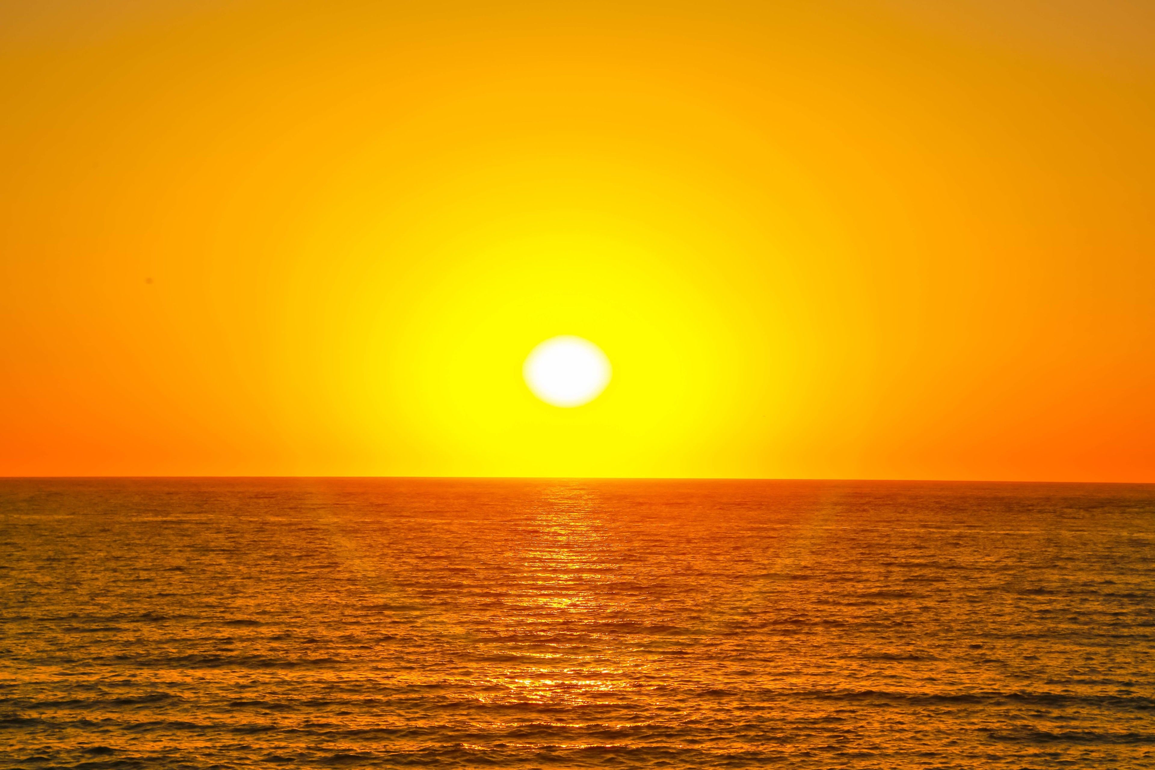 A sunset over the ocean with a clear sky.