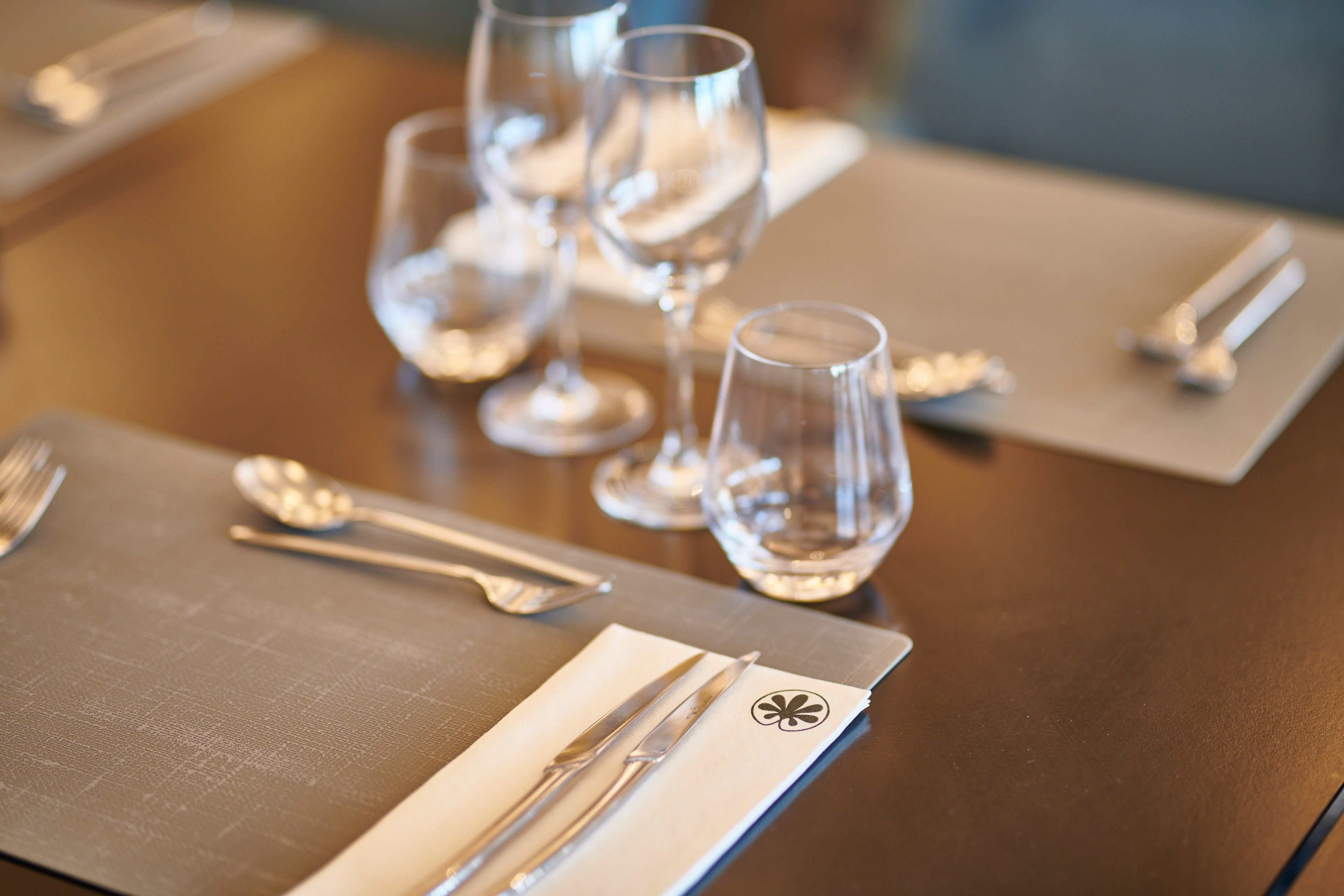 A neatly set dining table with cutlery and glasses.