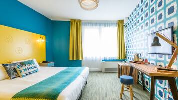 Een hotelkamer met een bed, bureau en een behang met patroon.