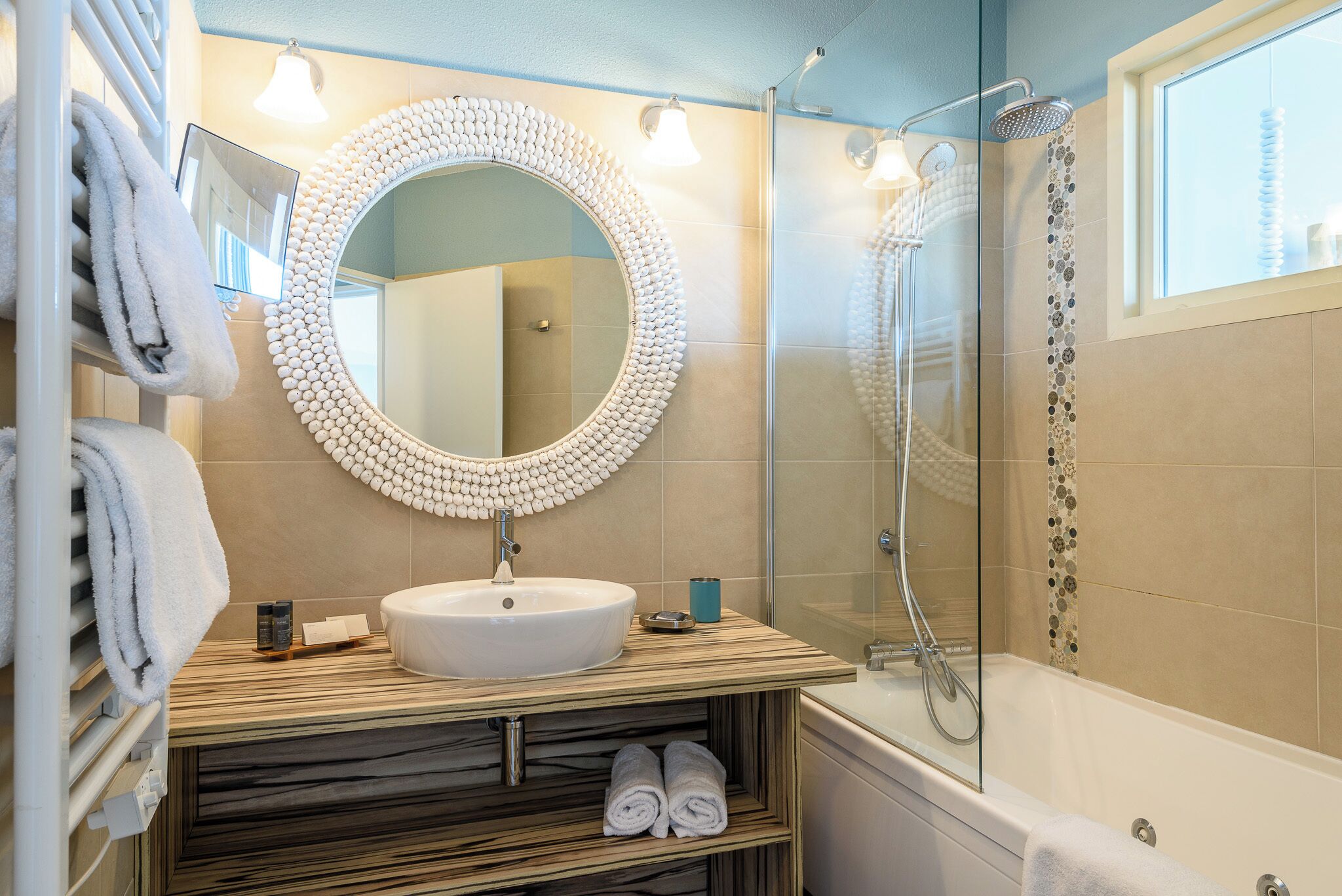 A bathroom with a round mirror, a sink, a shower, and a bathtub.