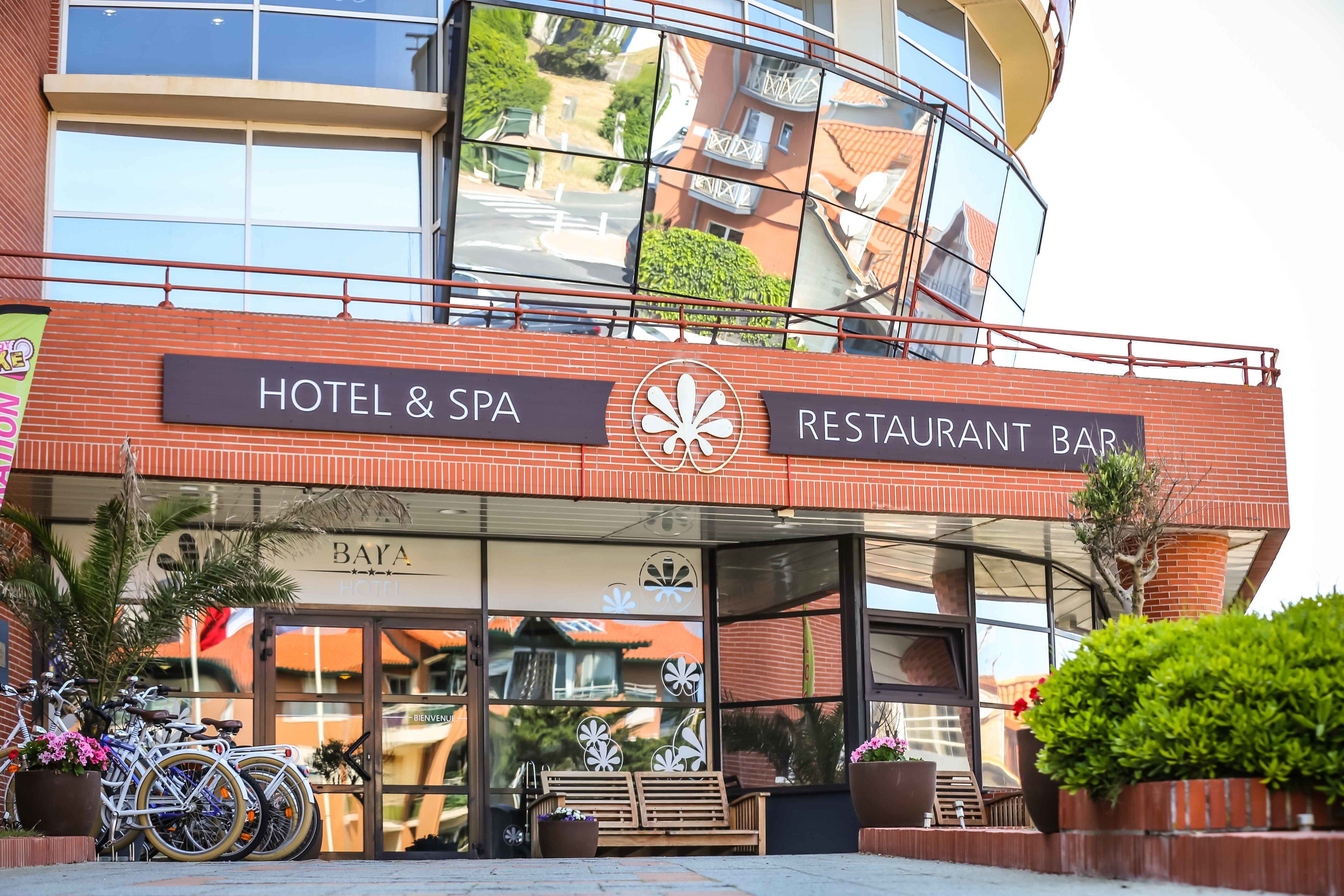 A hotel and spa with a restaurant bar, featuring a modern design with glass doors and a balcony.