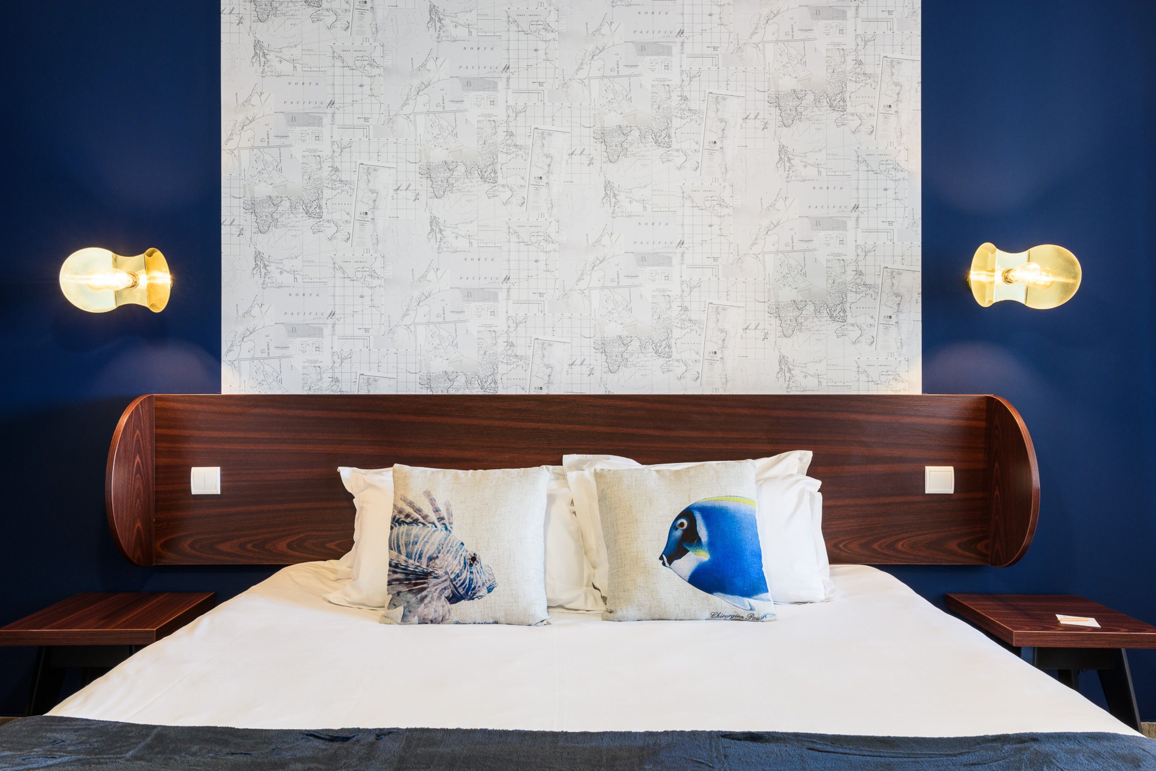 Una cama con cabecera de madera, dos mesitas de noche y un mapa grande en la pared.