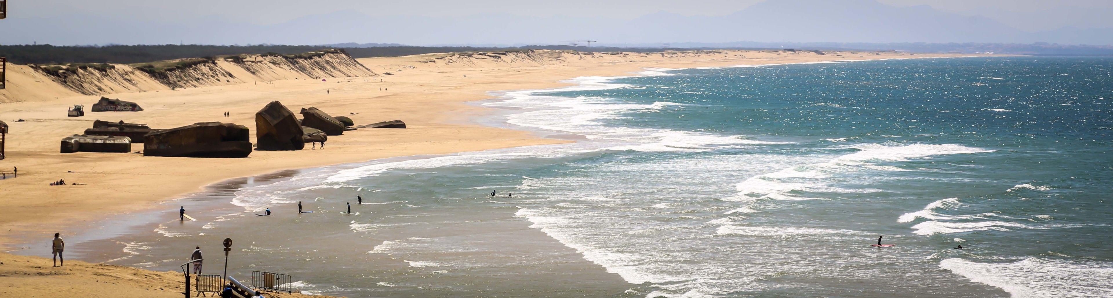 A beach with large rocks, a sandy shore, and the ocean.