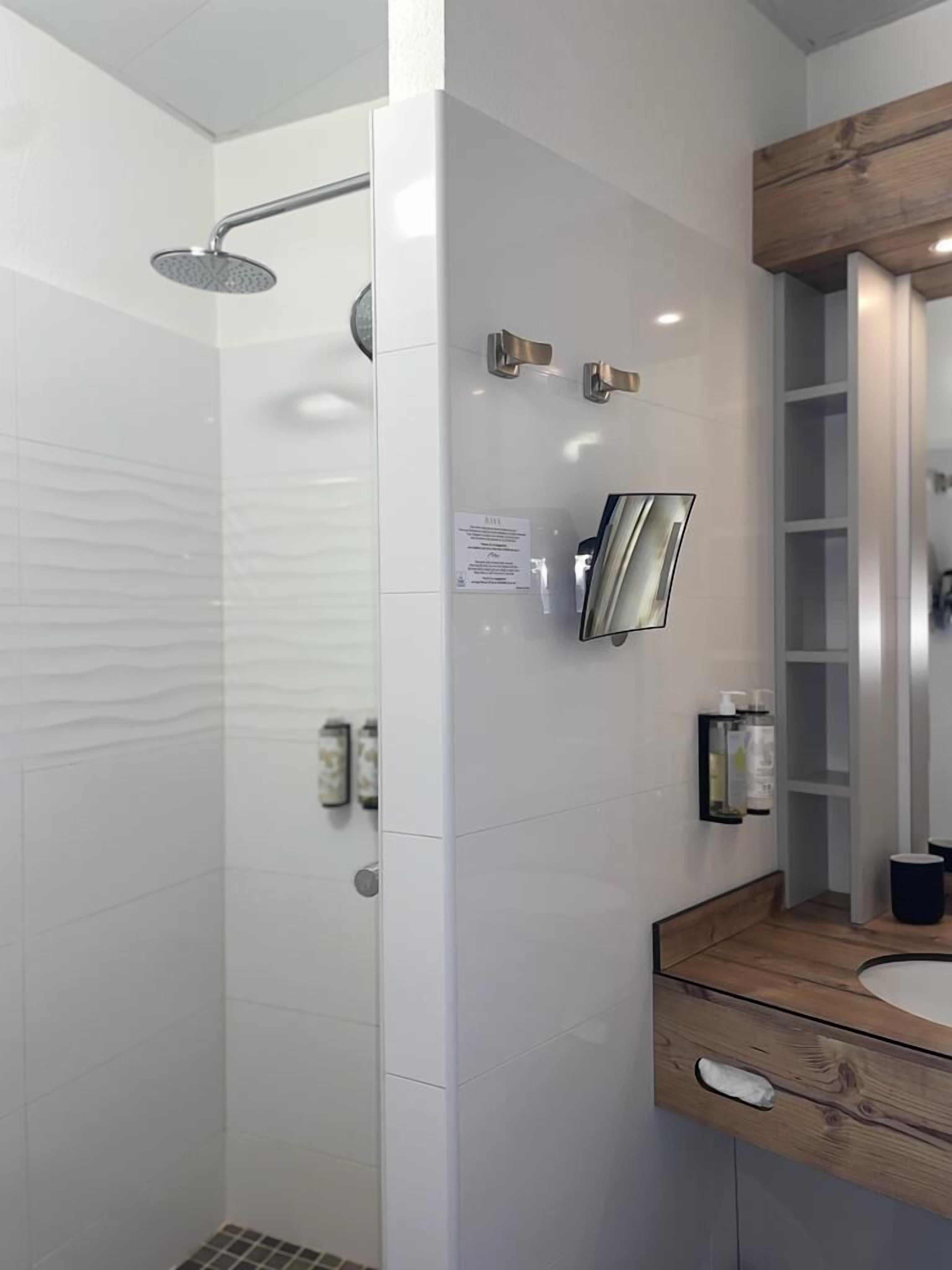 Un baño moderno con ducha, tocador de madera y espejo.