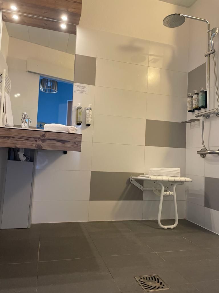 A modern bathroom with a shower, a sink with a wooden countertop, and a towel rack.