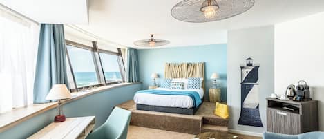 Ein modernes Hotelzimmer mit Bett, Sitzgelegenheit und Blick auf den Ozean.