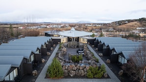 Een hotel met meerdere kamers gerangschikt in een U-vorm, een centrale binnenplaats met zitplaatsen en uitzicht op een besneeuwd berglandschap.
