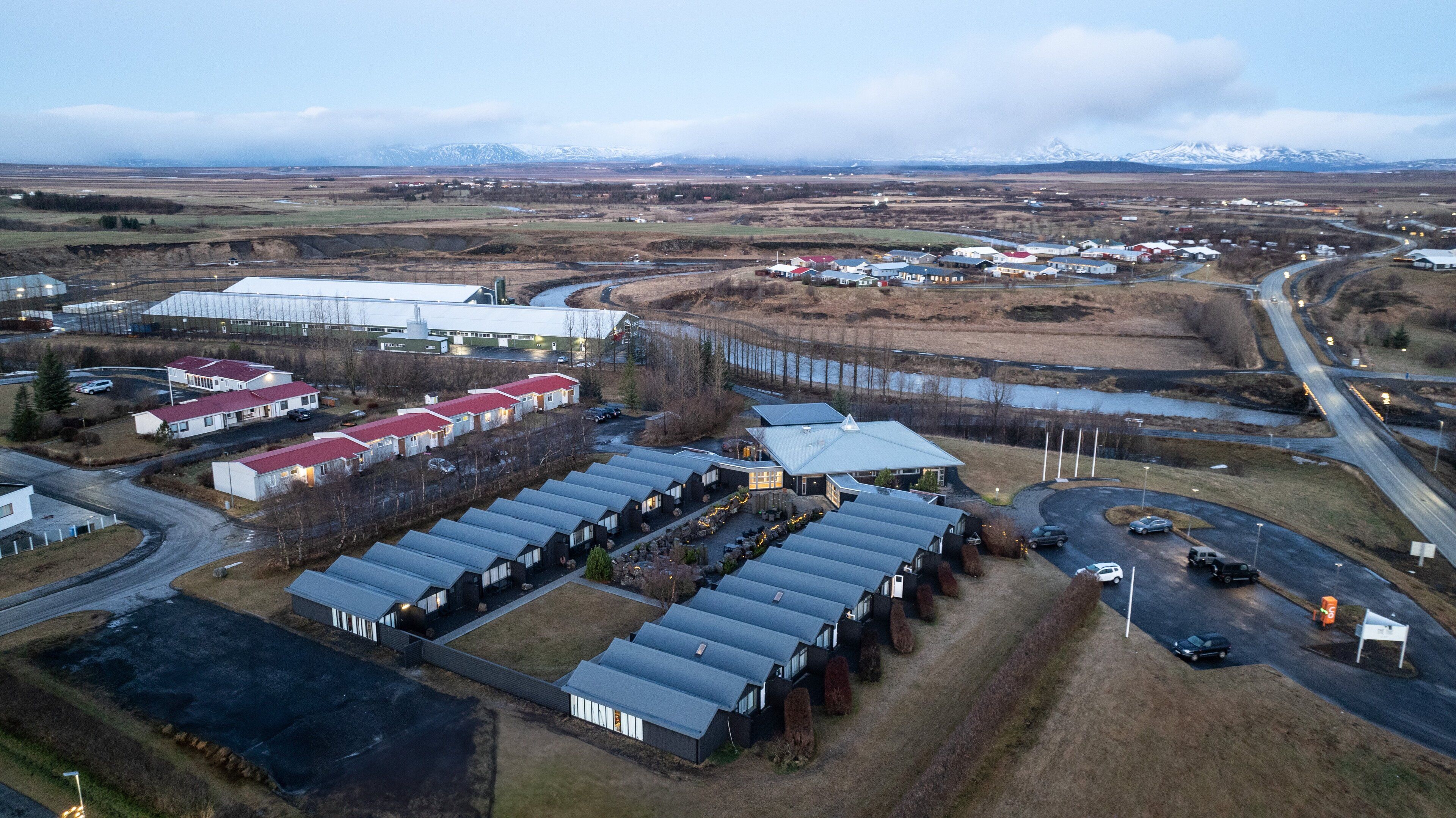 An industrial area with multiple buildings, including a large warehouse and several smaller structures with red roofs.