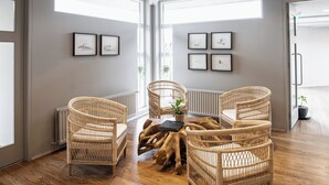 Een kamer met een hoge plafond, houten vloer en rieten stoelen.