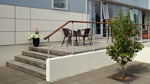 Un bâtiment moderne doté d’un escalier menant à un balcon avec des sièges extérieurs.