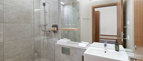 A modern bathroom with a glass-enclosed shower, a white sink, and a mirror above it.
