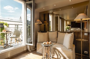 A modern living room with a sofa, two lamps, a small table with pastries, and a balcony with outdoor furniture. - B Montmartre (Paris)