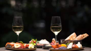 Una mesa con diversos alimentos y dos copas de vino blanco, sobre un fondo oscuro.