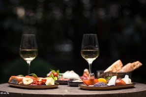A table with various food items and two glasses of white wine, set against a dark background. - B Montmartre (Paris)