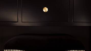 Un fauteuil noir recouvert de tissu, orné d’un bouton doré et d’une bordure à motifs.