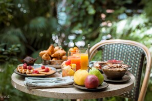 A round table with breakfast items including waffles, fruit, and a bowl of cereal. - B Montmartre (Paris)