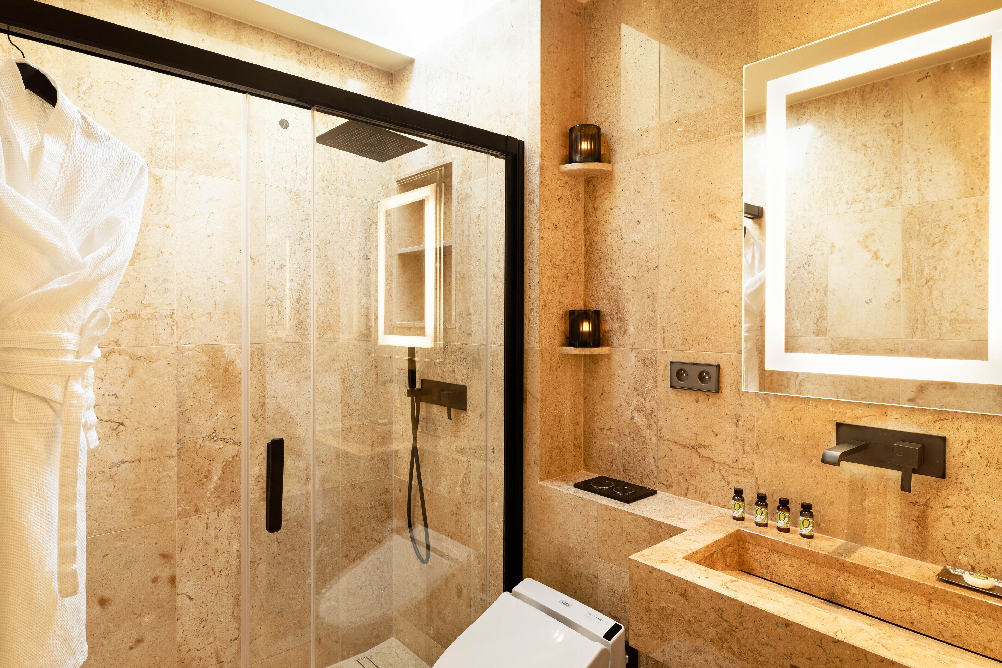 A modern bathroom with a glass-enclosed shower, a marble sink, and a large mirror.
