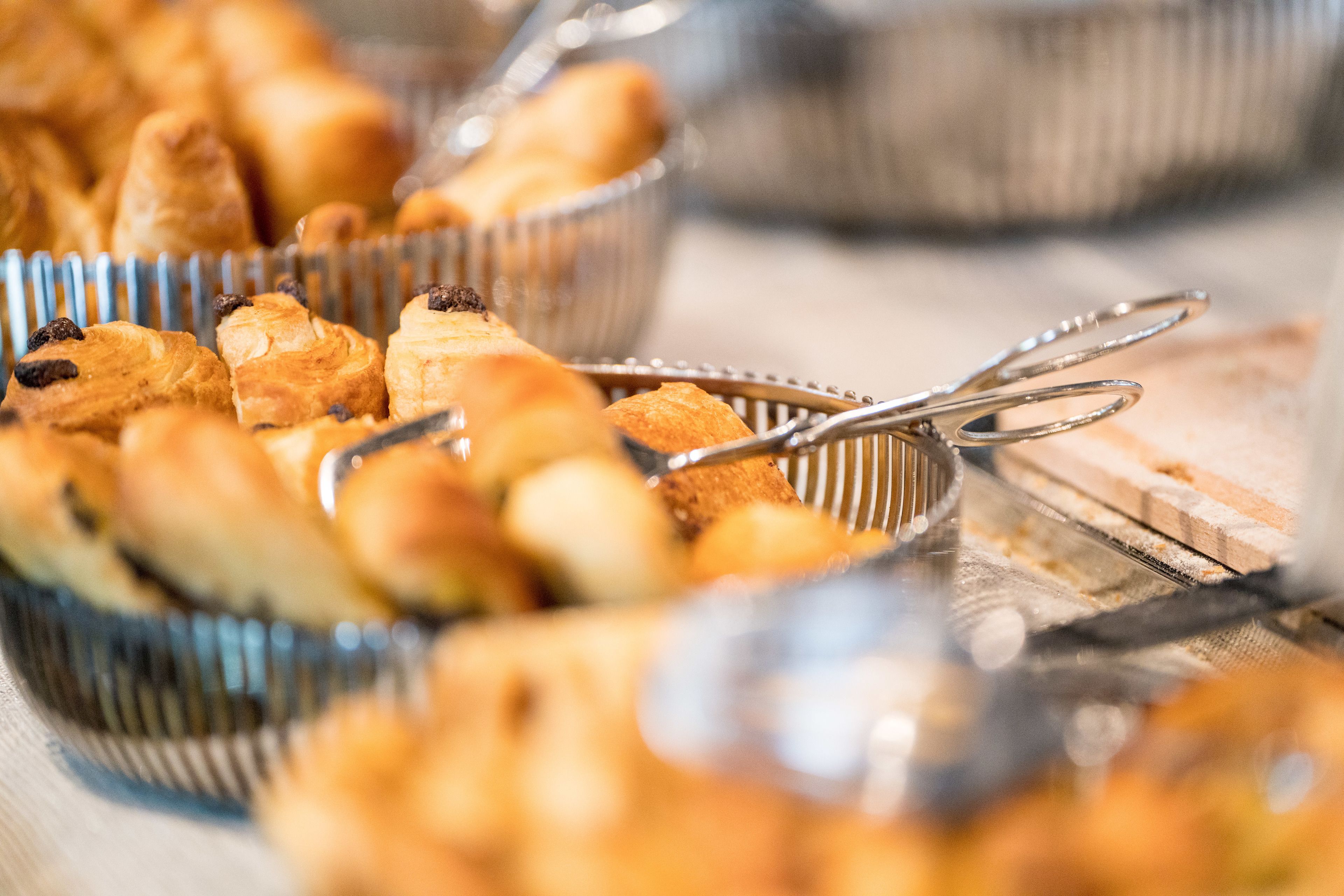 A buffet with various baked goods, including pastries and bread, arranged on a table.