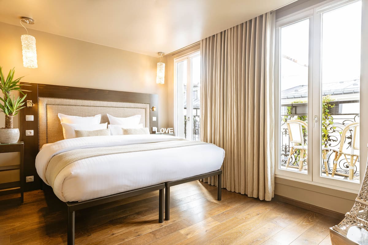 Quarto de hotel com uma cama grande, uma mesa de cabeceira com abajur e vista para a varanda.