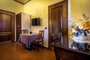 Un comedor con una mesa, sillas, un televisor montado en la pared y un arreglo floral decorativo.
