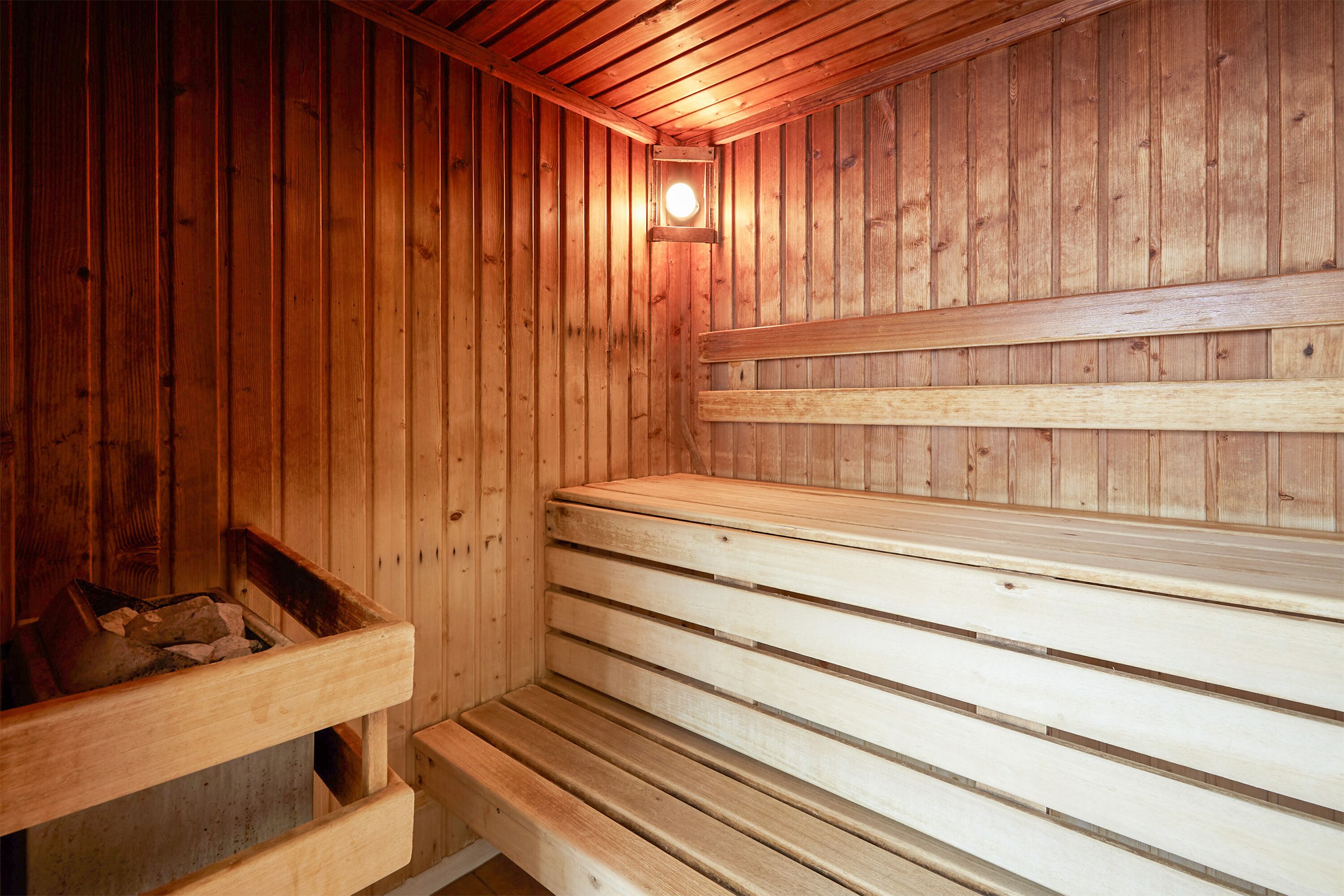 Un sauna avec des bancs en bois et un banc doté d’un compartiment de rangement.