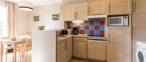 A modern kitchen with wooden cabinets, a microwave, a dishwasher, and a washing machine.