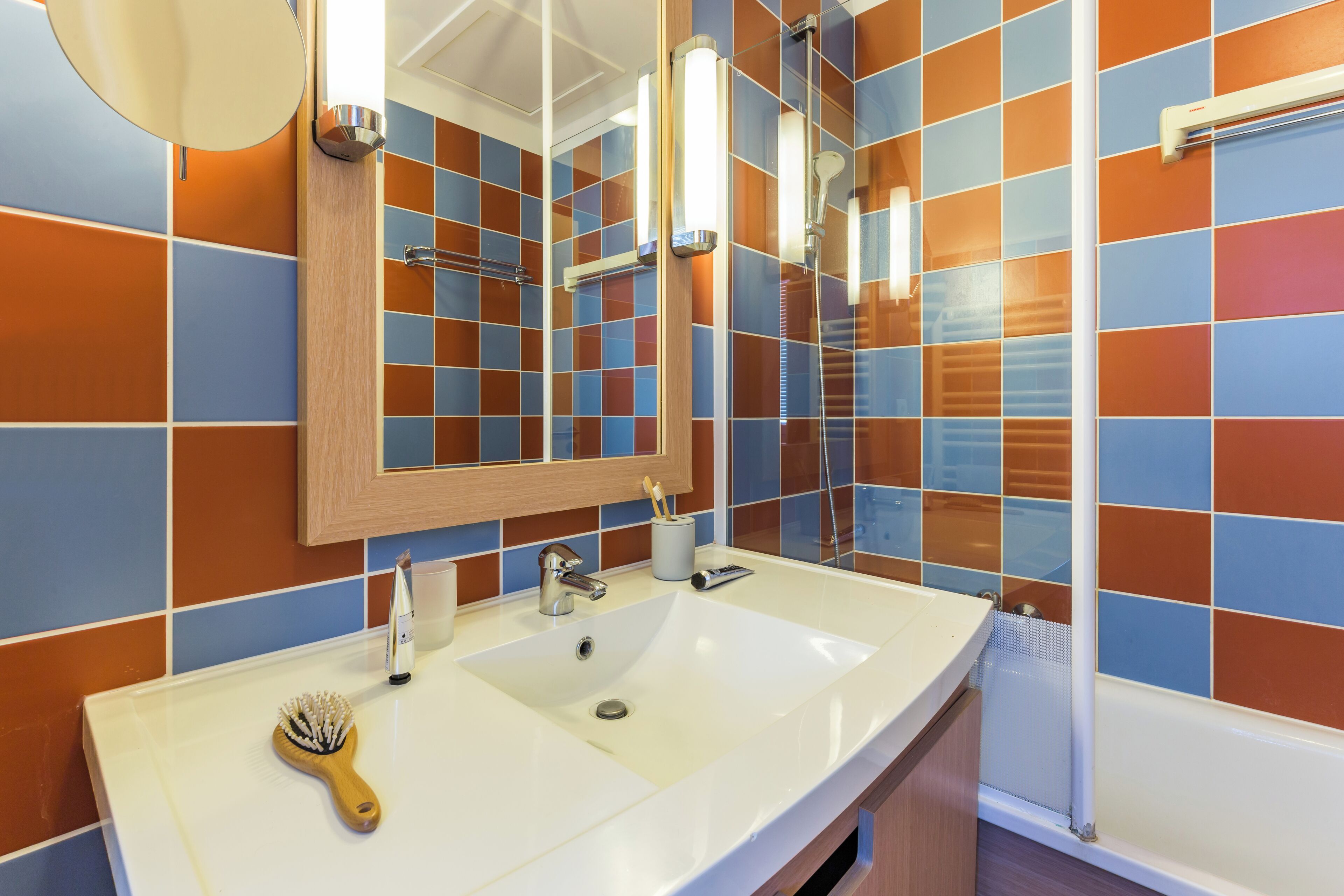 A bathroom with a white sink, a mirror, and a shower.