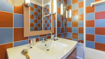 A bathroom with a white sink, a mirror, and a shower.