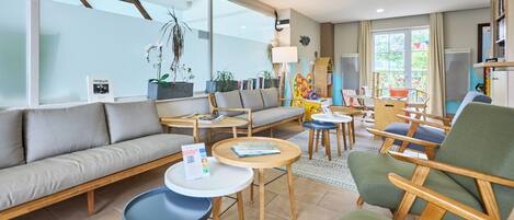 Un salon moderne comprenant un canapé, des fauteuils, une table basse et une bibliothèque.