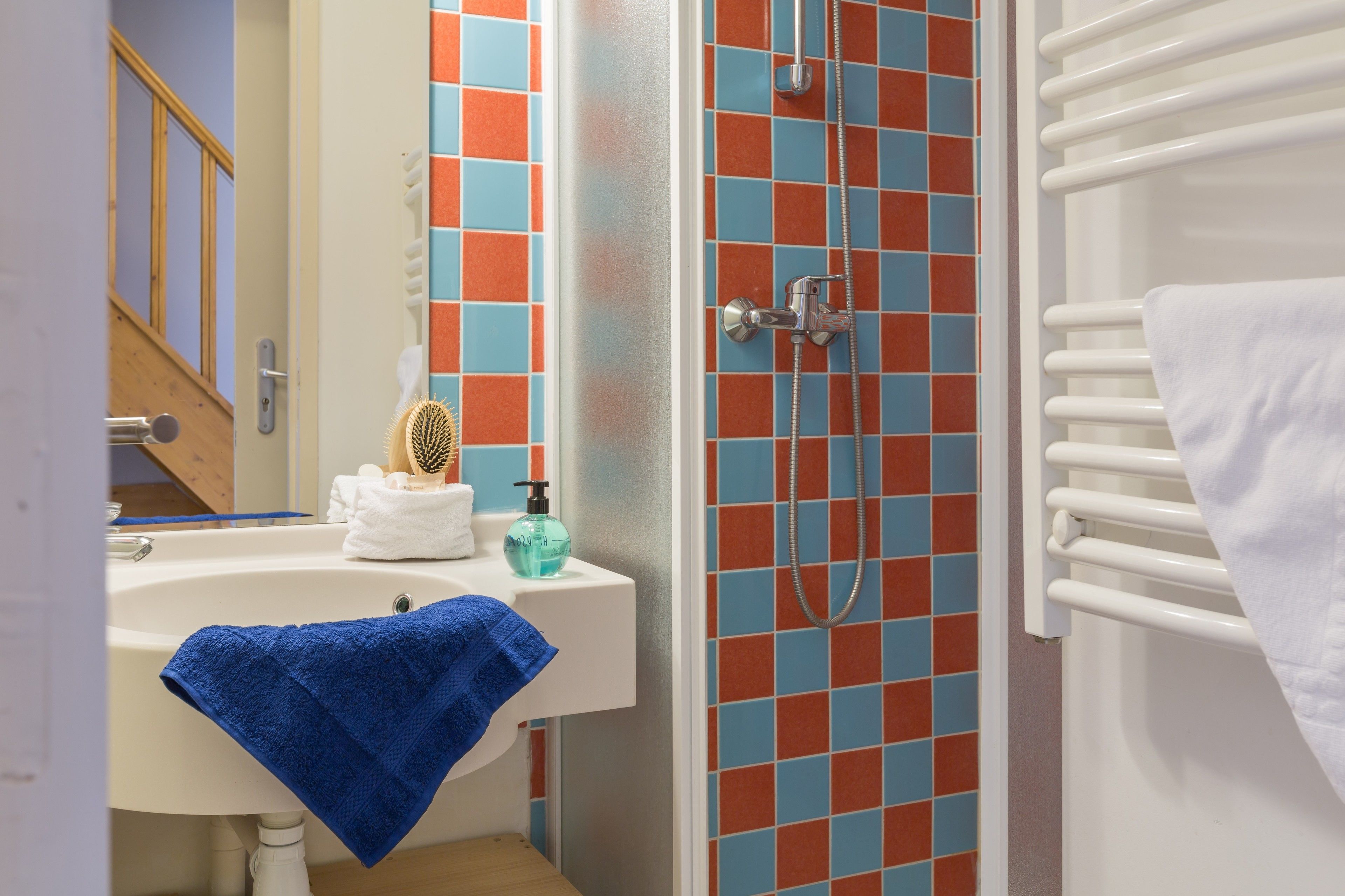 A bathroom with a sink, mirror, and shower.