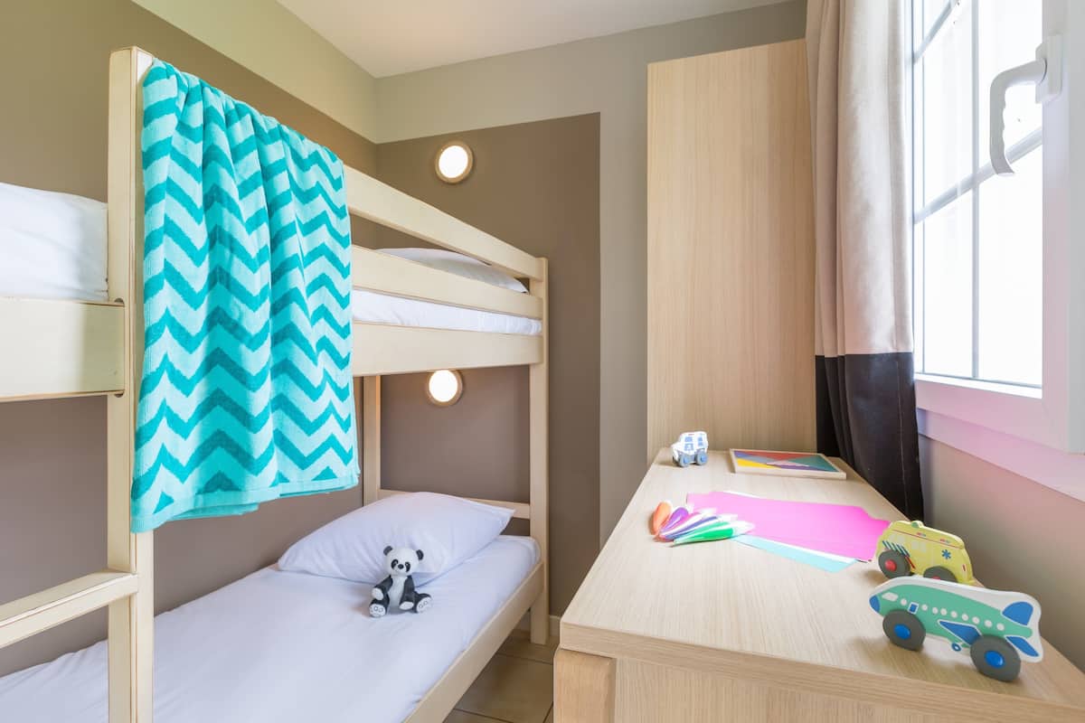 A bunk bed room with a desk and toys.